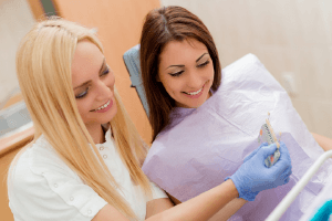 Woman and dental assistant looking at tooth color chart