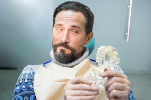 Man raising his eyebrows at a model of dentures