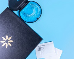 Invisalign trays in carrying case on blue surface next to packets of cleaning crystals