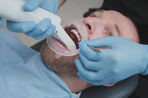 a dentist using a digital scanner on a patient 
