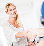 Blonde woman shaking hands with person at reception desk