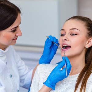 A dental hygienist cleaning a female patient’s mouth