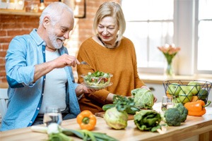 An older man and his wife preparing a salad