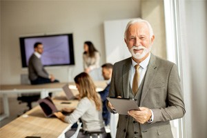 A senior businessman working on a digital tablet in a conference room