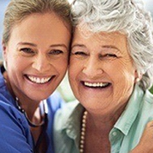 A middle-aged woman and her mother hugging and smiling after the eldest received her customized dentures