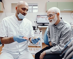 An older man listening to his dentist discuss the potential for new dentures in Carrollton