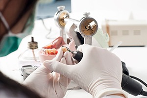a dental lab technician polishing denture teeth