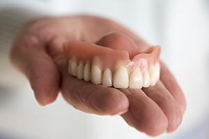 Hand holding full dentures