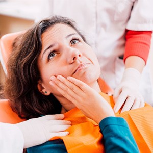 Woman with oral pain visiting dentist for dental implant salvage in Carrollton, TX
