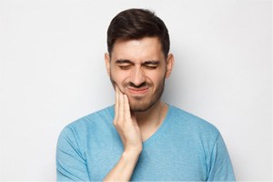 Man rubbing jaw due to oral pain