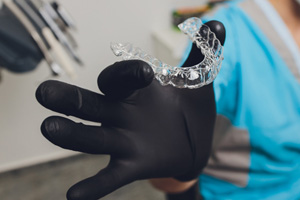 Dentist holding a clear aligner in their gloved hand 