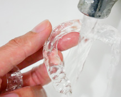 Person rinsing off their clear aligners 