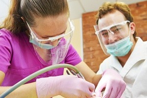 Two dentists performing dental work on a patient