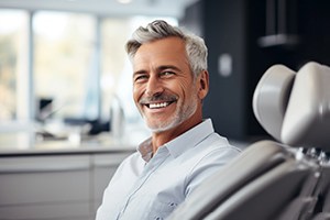 a man smiling and sitting in a dental chair