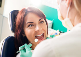 Woman smiling while dentist looks at her mouth