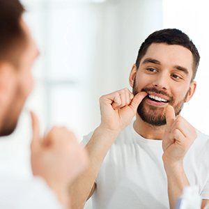 Man flossing in front of mirror