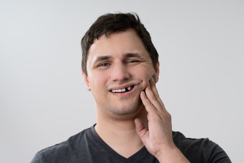 a young man holding his jaw while exposing the area of his knocked-out tooth