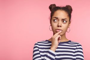 young woman thinking against peach background 