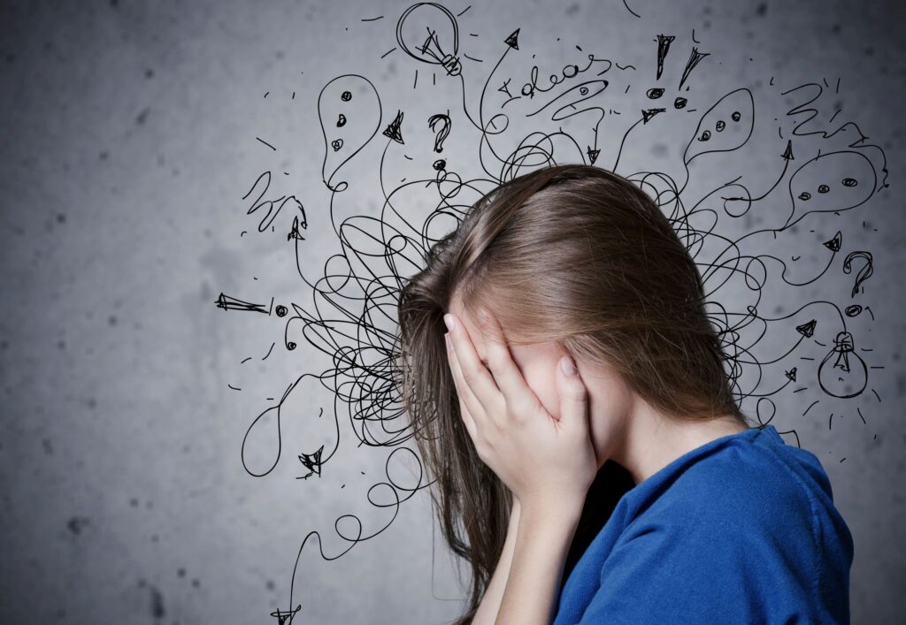 Woman with face in hands with stress scribbles around her head