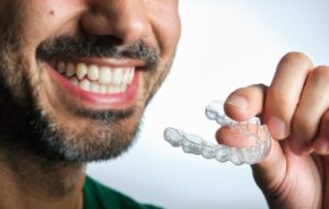 Man smiling while putting on his Invisalign